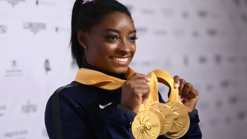 Simone Biles holding her Olympic and World medals, representing the victories earned through Simone Biles' childhood secret training story.