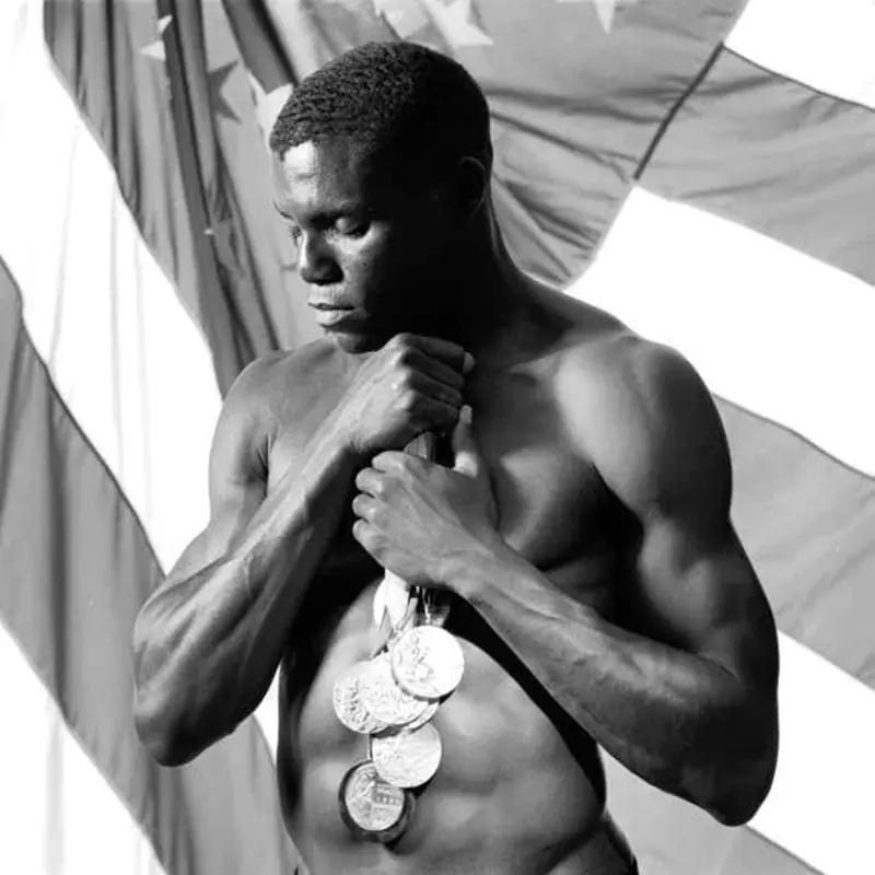 Carl Lewis holding his Olympic golds, representing the peak result of hidden habits from Carl Lewis’ track beginnings